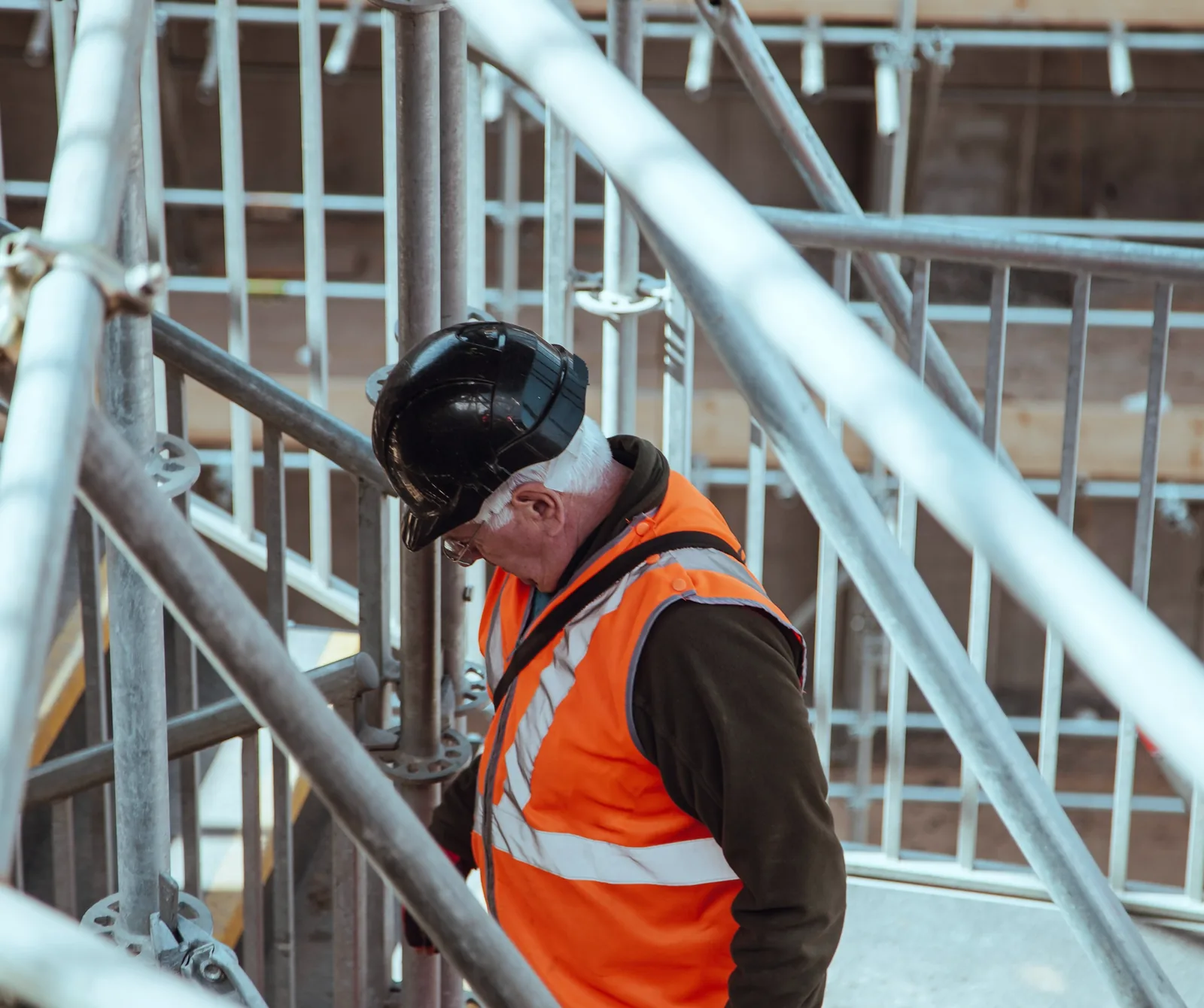 Worker in a hard hat and hi-vis vest inspecting scaffolding