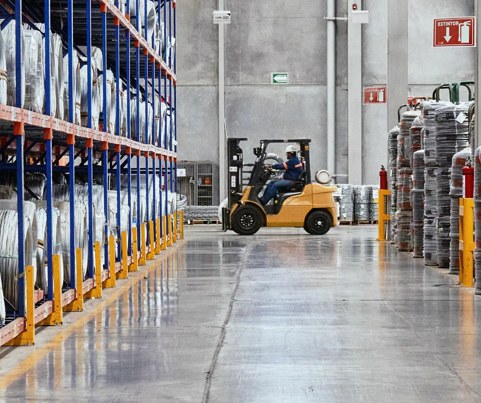 Forklift operator in a hard hat driving down a racking aisle