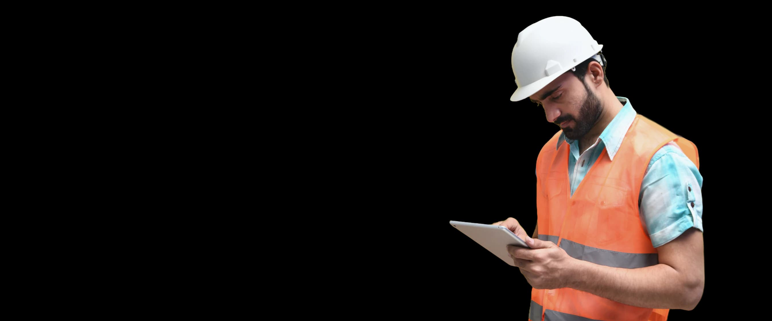 Safety professional in a hard hat and hi-vis vest checking a tablet