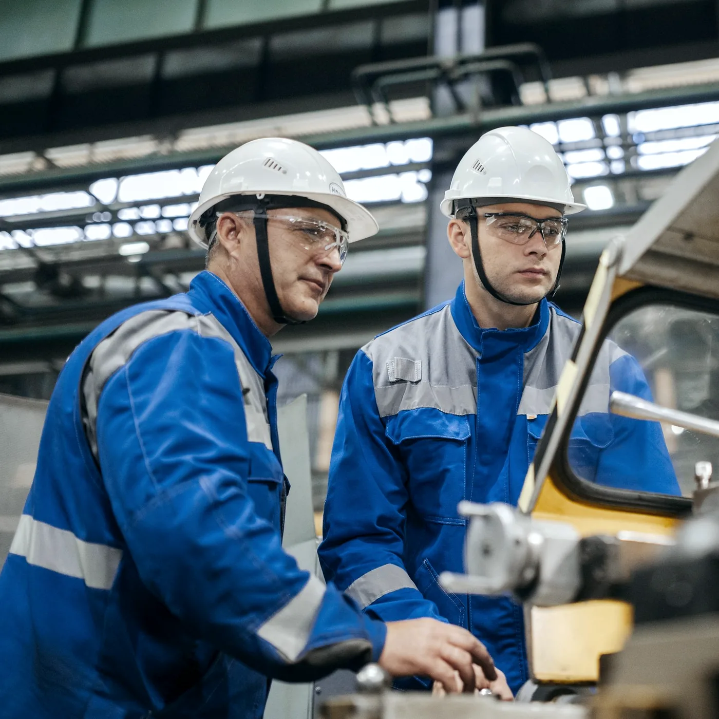 Supervisor and worker checking a machine together