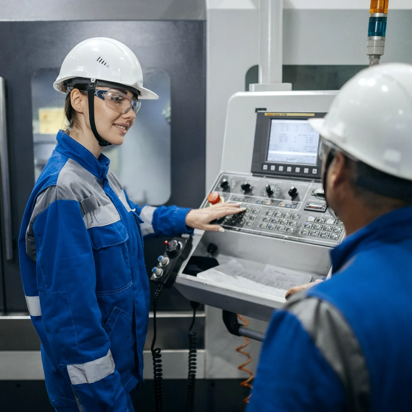Supervisor observing an operator at a machine control panel