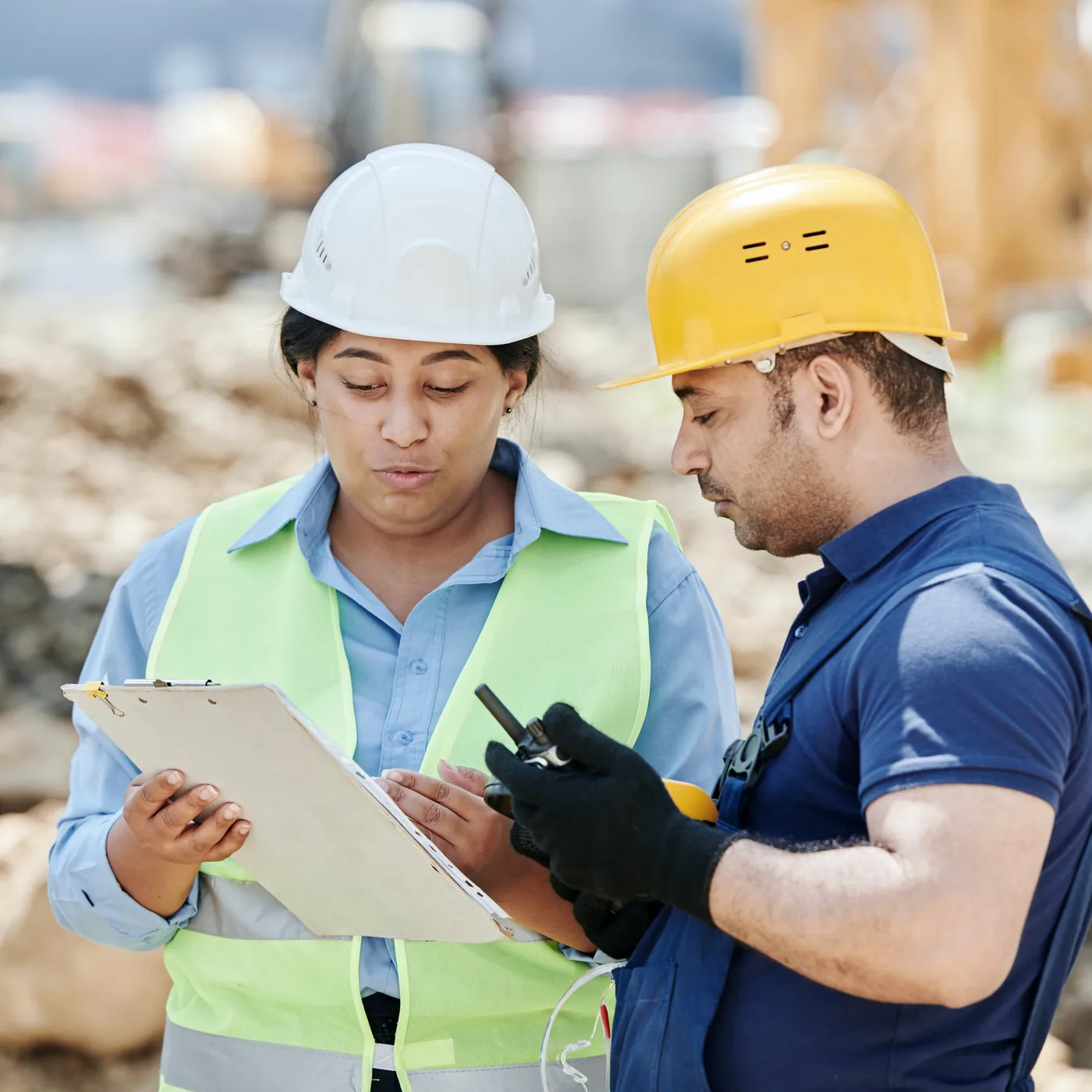 Two workers in hard hats talking through a checklist on site