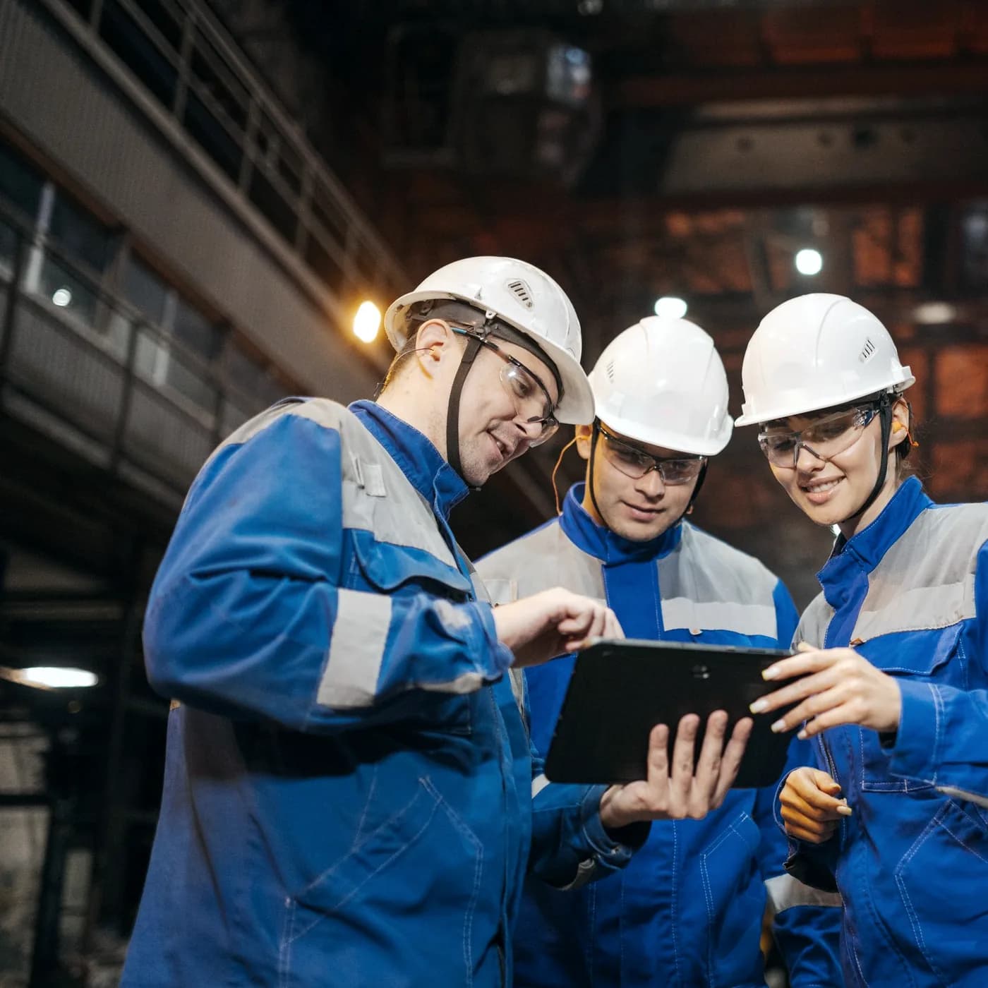 Three workers in full PPE reviewing an incident together on a tablet