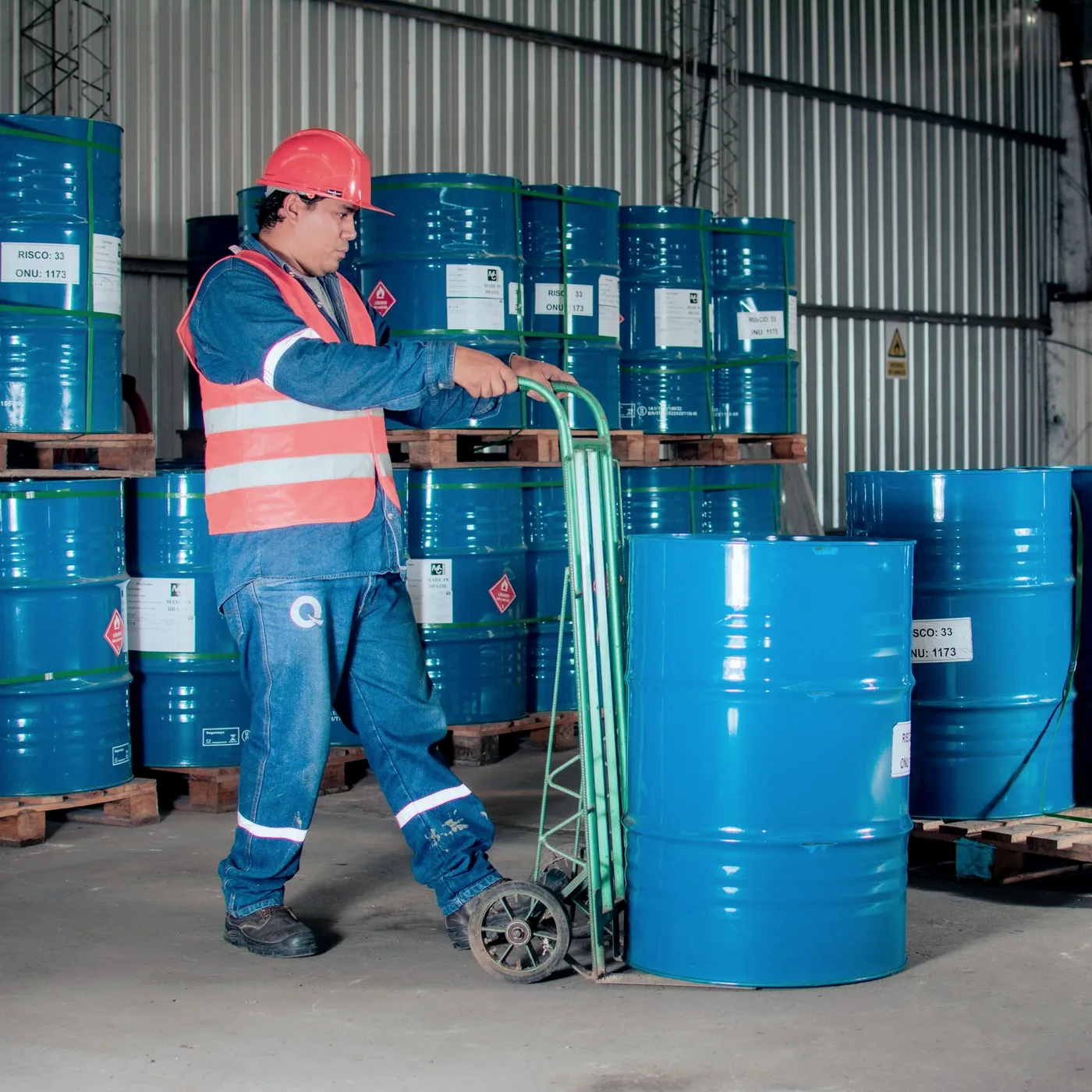 Worker moving chemical drums marked with flammable hazard labels